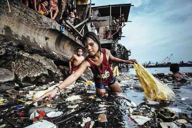 Une fillette ramasse les déchets plastiques dans les eaux marines de Manille au Philippines (2019) © Hartmut Schwarzbach Une fillette ramasse les déchets plastiques dans les eaux marines de Manille au Philippines (2019) © Hartmut Schwarzbach