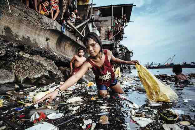 Une fillette ramasse les déchets plastiques dans les eaux marines de Manille au Philippines (2019) © Hartmut Schwarzbach